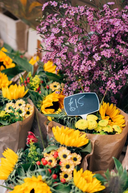 A vibrant display of freshly arranged flower bouquets at a local florist, featuring yellow sunflowers with large, bright petals and dark centers, mixed with smaller white and yellow daisies and sprigs