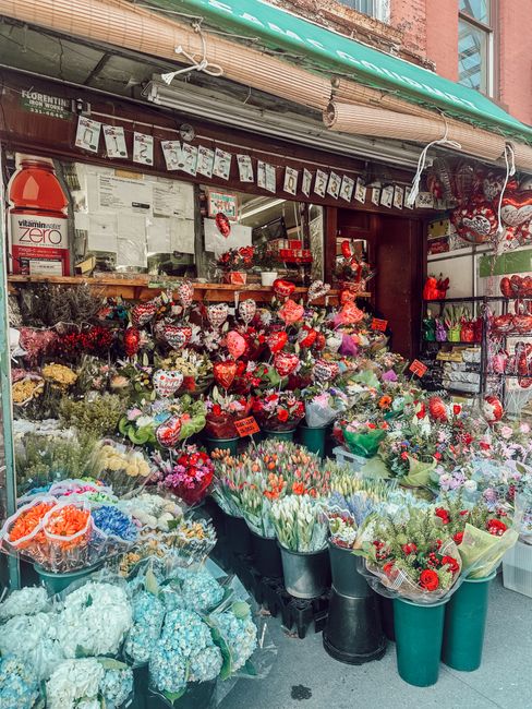 A vibrant display of fresh flowers at Belgravia Flowers, featuring a variety of floral arrangements including red, pink, and white roses, tulips, and decorative bouquets. The flowers are arranged in b